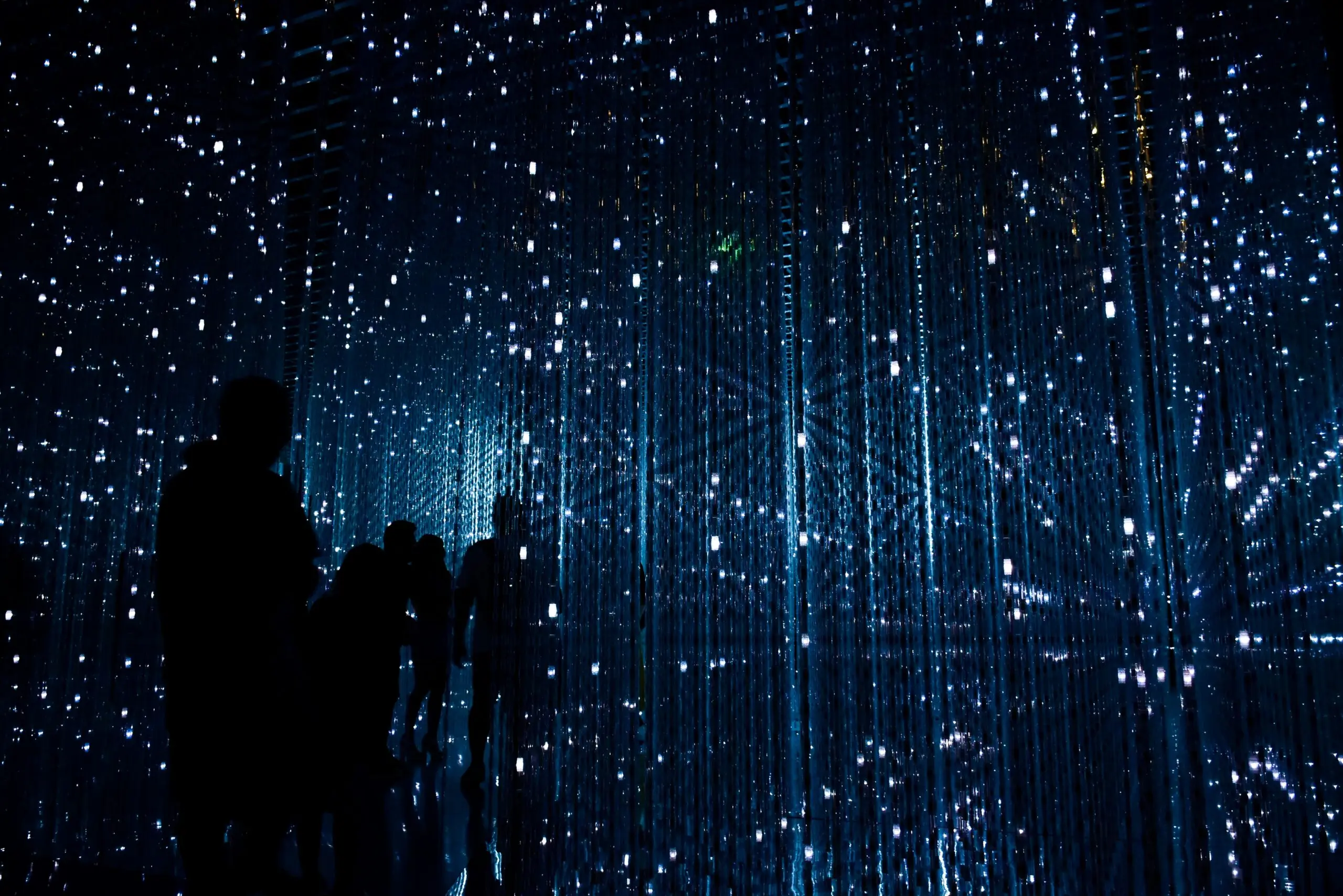 Immersive Kunstinstallation "Infinite Crystal Universe" von teamLab, die für ihre vertikalen Lichtstreben und Spiegel bekannt ist.